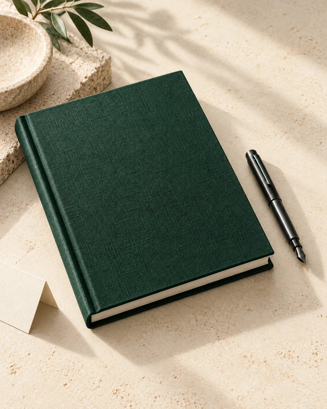 Cuốn brand book bìa xanh rừng trên bề mặt đá màu kem